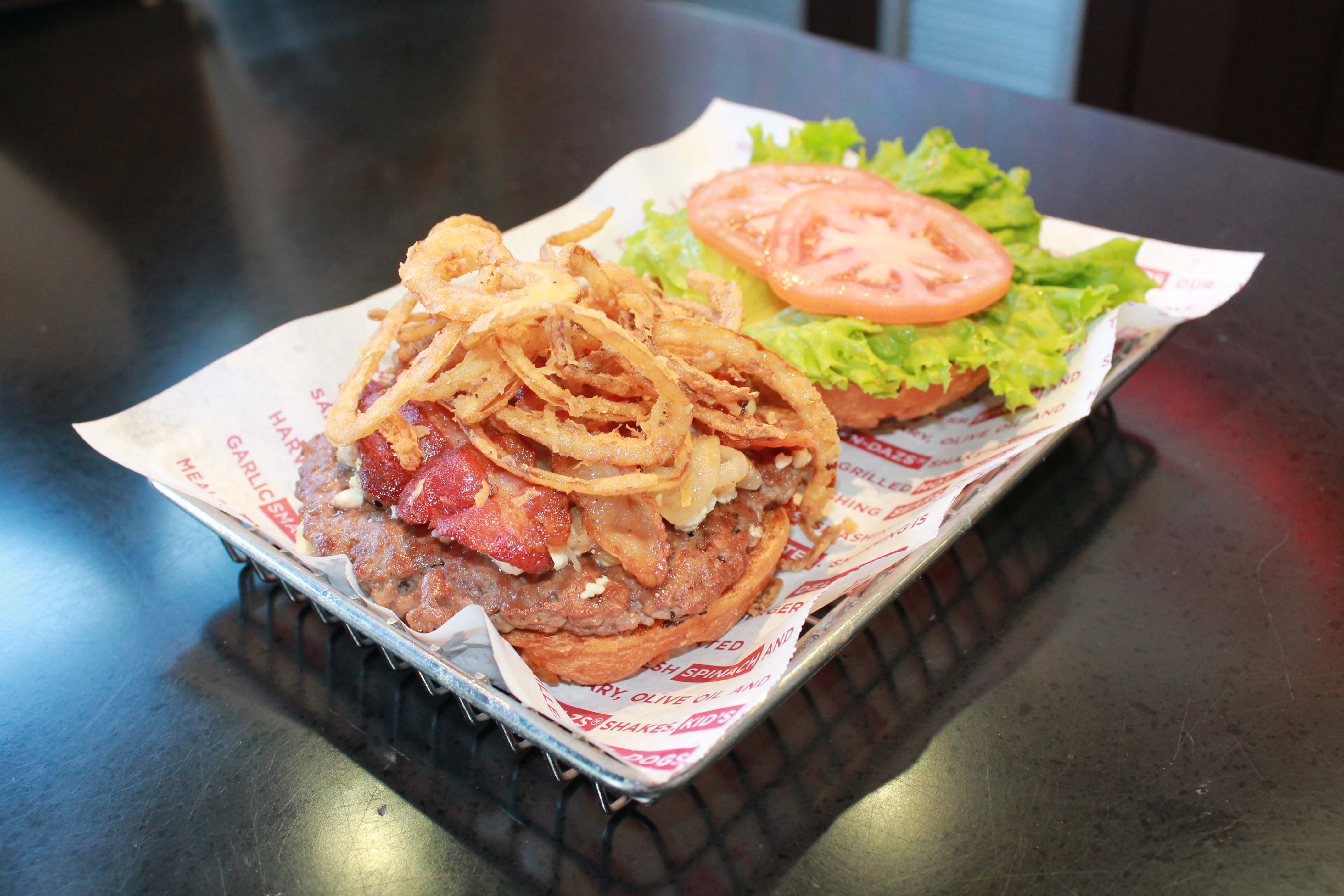 Smashburger's newly-renamed Boston Burger features Applewood-smoked bacon, blue cheese, grilled onions, haystack onions, lettuce, tomato and mayo on an onion bun. photo credit: Smashburger